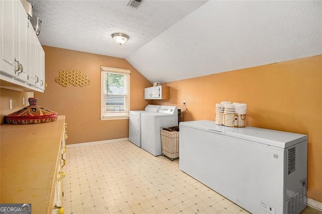 clothes washing area with a textured ceiling, baseboards, cabinet space, light floors, and washing machine and clothes dryer