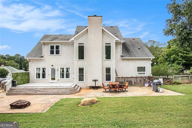 rear view of house with a chimney, a patio area, a lawn, and a fire pit