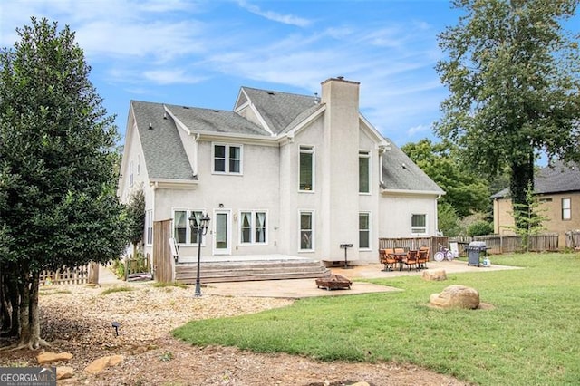 back of property with a patio, a chimney, a lawn, an outdoor fire pit, and fence