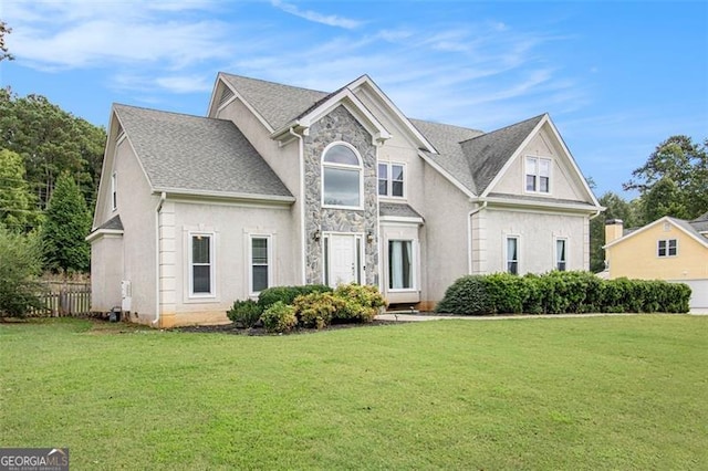 view of front of property featuring stone siding, fence, a front lawn, and stucco siding