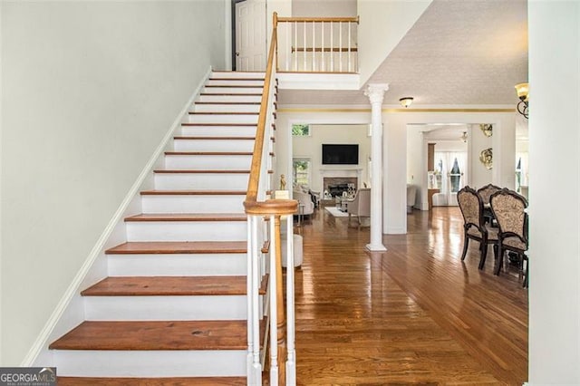 stairway with hardwood / wood-style floors and ornate columns