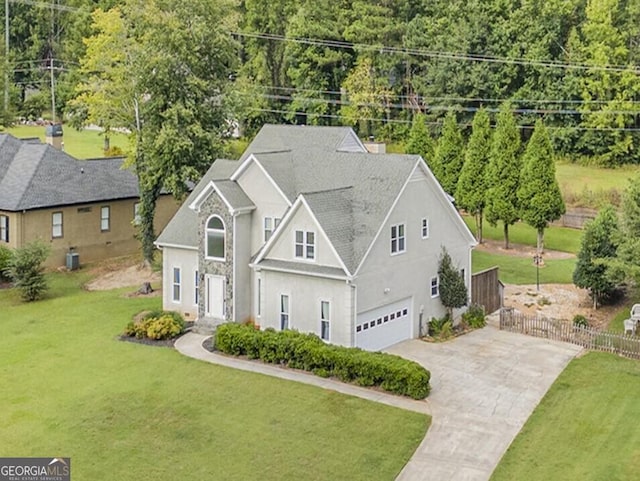 view of front of property with an attached garage, concrete driveway, central AC, and a front yard