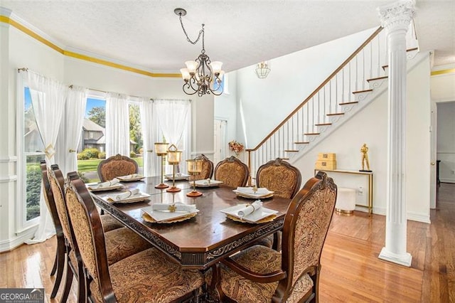 dining space with light wood-style flooring, stairs, ornamental molding, and a textured ceiling