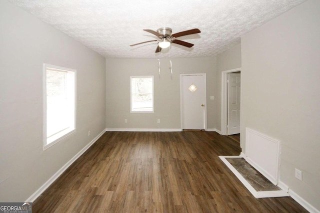 empty room with a textured ceiling, dark hardwood / wood-style floors, and ceiling fan