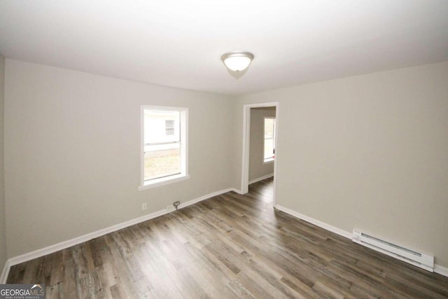 unfurnished room with a baseboard heating unit and dark hardwood / wood-style flooring