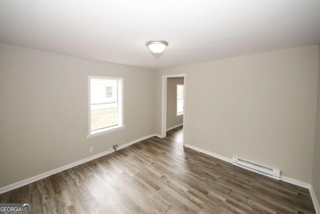 unfurnished room with a baseboard radiator and dark hardwood / wood-style floors