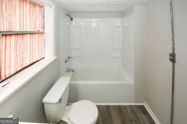 bathroom with a textured ceiling, shower / tub combination, hardwood / wood-style floors, and toilet