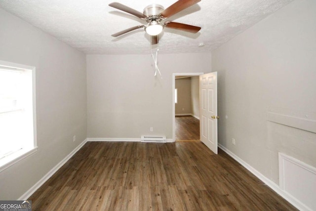 empty room with a textured ceiling, baseboard heating, and dark hardwood / wood-style flooring