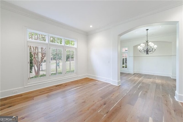 unfurnished room featuring a notable chandelier, light hardwood / wood-style floors, and crown molding