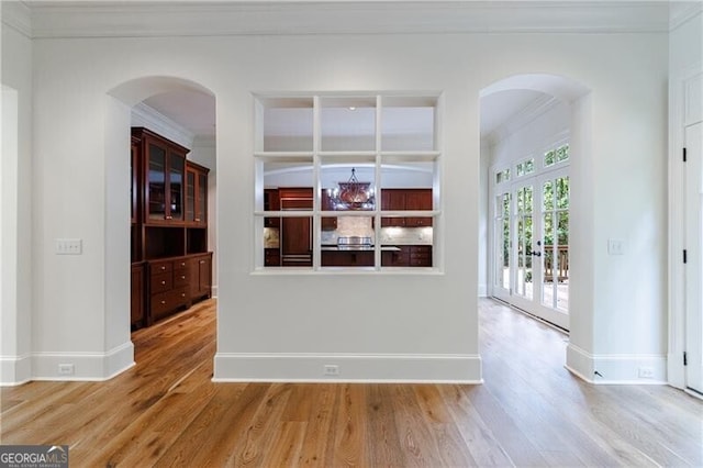 interior space featuring hardwood / wood-style flooring, ornamental molding, and french doors