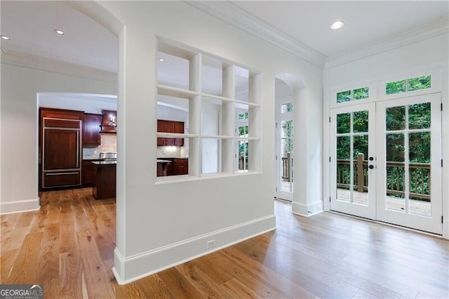 interior space with french doors, light hardwood / wood-style floors, and ornamental molding