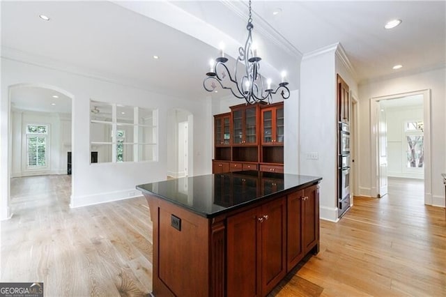 kitchen featuring pendant lighting, a center island, an inviting chandelier, crown molding, and light hardwood / wood-style floors