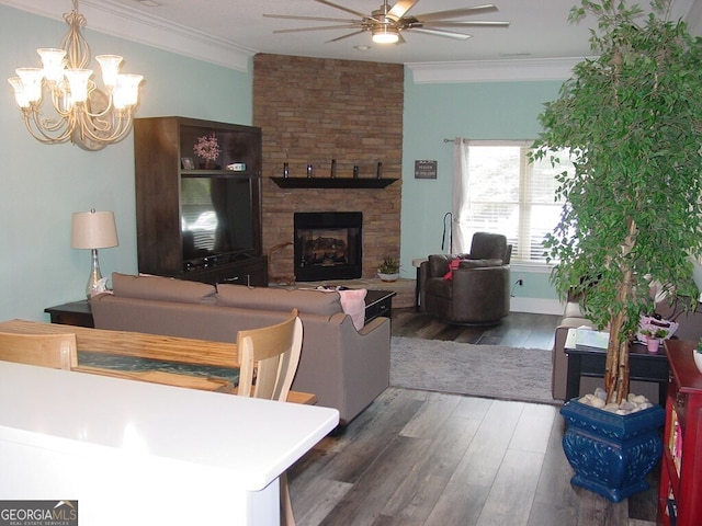 living room featuring wood-type flooring, ceiling fan with notable chandelier, a fireplace, and ornamental molding