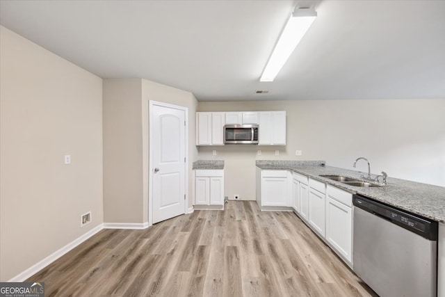 kitchen with white cabinets, appliances with stainless steel finishes, light wood-type flooring, and sink