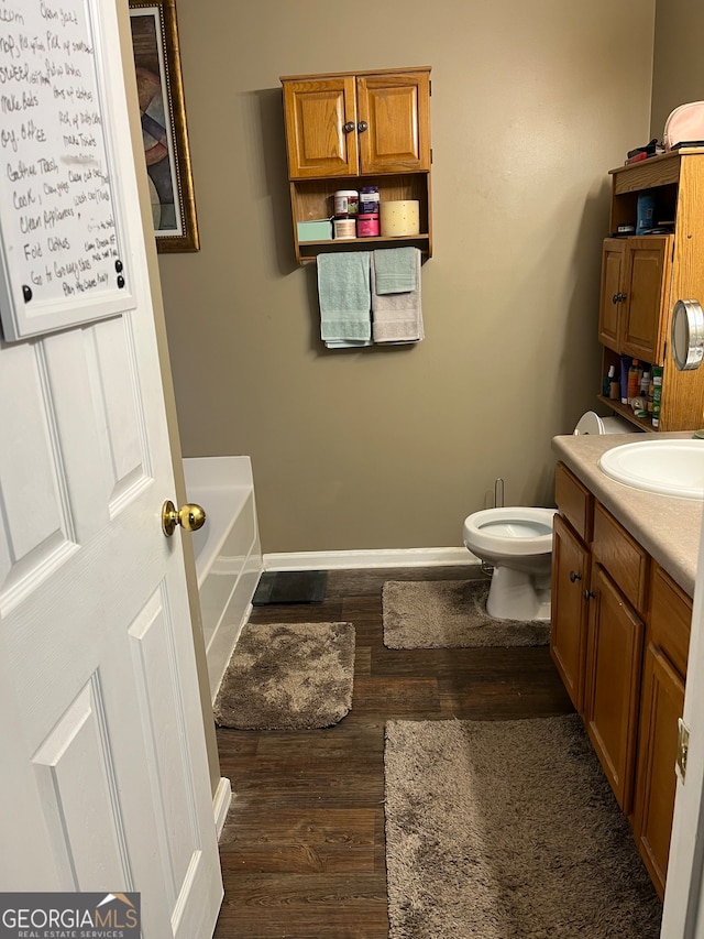 bathroom featuring a bathtub, wood-type flooring, vanity, and toilet