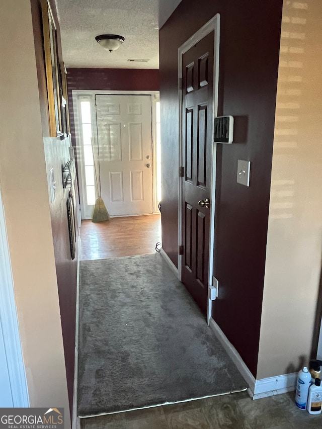 corridor with dark carpet and a textured ceiling