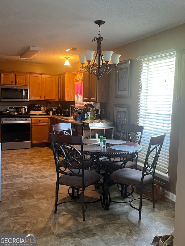 dining room with a textured ceiling, sink, and a chandelier