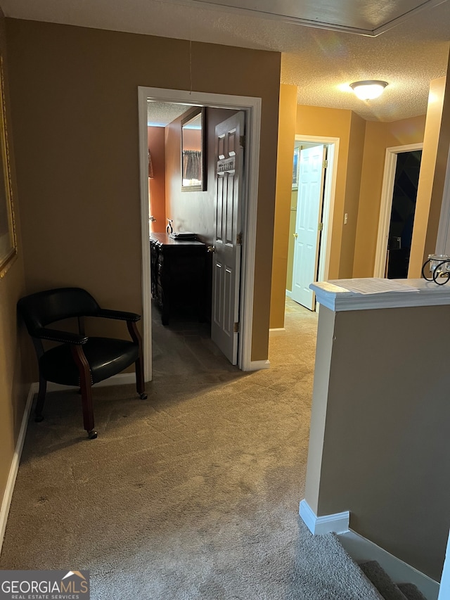 hallway featuring a textured ceiling and light colored carpet