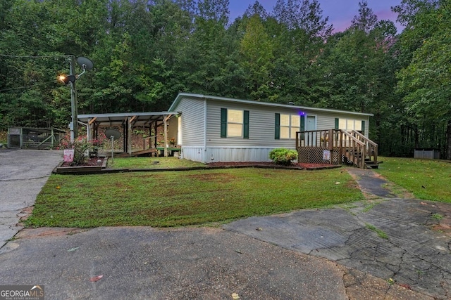 manufactured / mobile home featuring a lawn and a carport