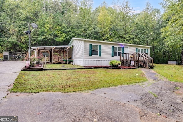 manufactured / mobile home with a carport, a wooden deck, and a front yard