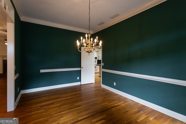 empty room featuring an inviting chandelier, crown molding, and dark hardwood / wood-style floors