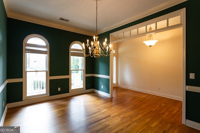 empty room with ornamental molding, a chandelier, and hardwood / wood-style floors