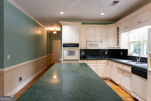 kitchen featuring light hardwood / wood-style floors, tasteful backsplash, sink, white appliances, and crown molding