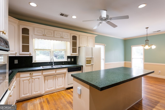 kitchen with sink, white appliances, a kitchen island, light hardwood / wood-style flooring, and crown molding