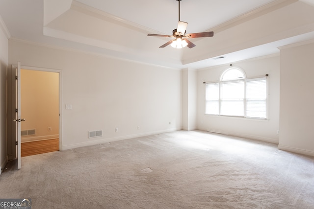 carpeted spare room with ceiling fan, a raised ceiling, and ornamental molding