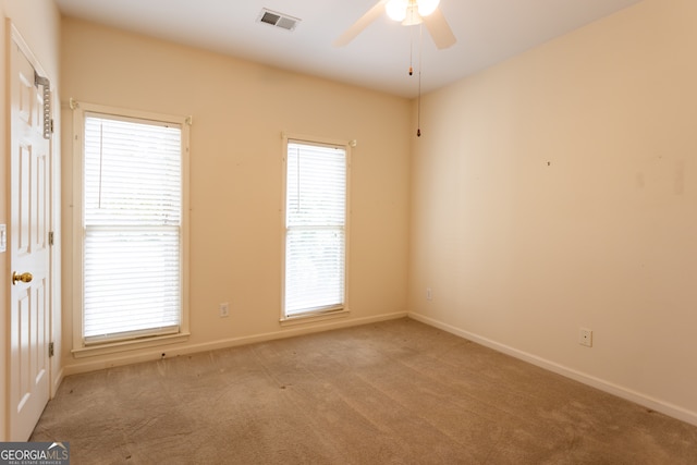 empty room with a healthy amount of sunlight, ceiling fan, and light colored carpet