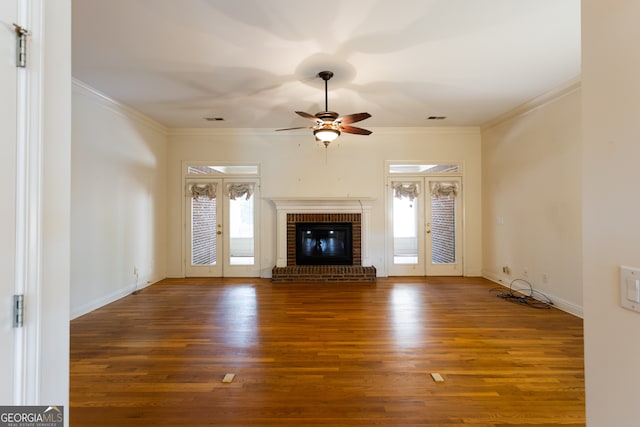 unfurnished living room featuring hardwood / wood-style flooring, a brick fireplace, and a wealth of natural light