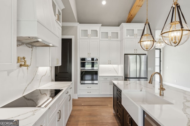 kitchen with pendant lighting, sink, white cabinetry, stainless steel appliances, and light stone countertops