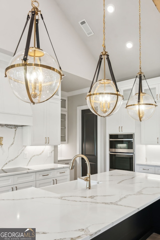 kitchen featuring pendant lighting, light stone counters, stovetop, and white cabinets