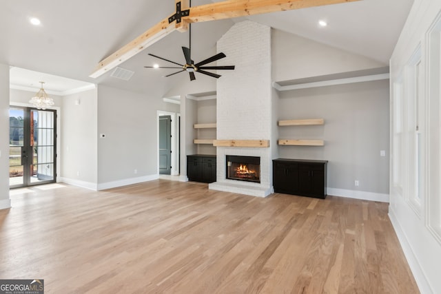 unfurnished living room with beam ceiling, high vaulted ceiling, light hardwood / wood-style flooring, a fireplace, and ceiling fan with notable chandelier