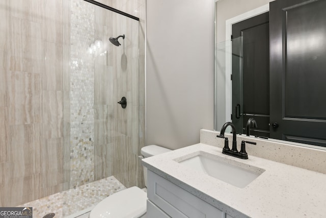 bathroom with tiled shower, vanity, and toilet