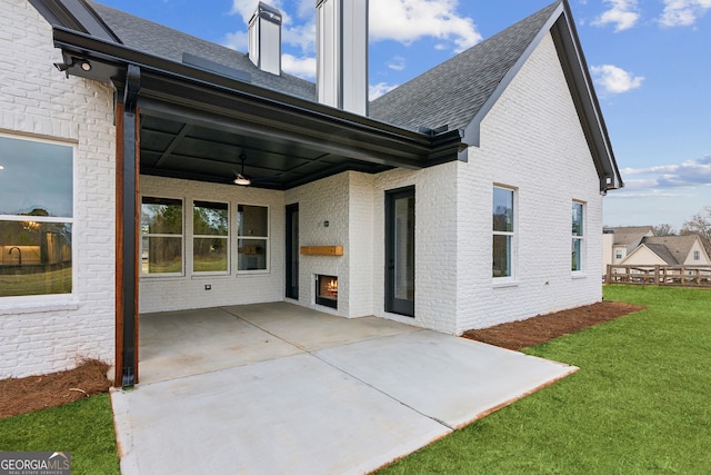 back of property featuring a lawn, a fireplace, ceiling fan, and a patio area