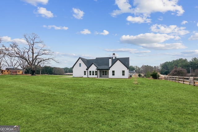 back of house with a lawn and a rural view