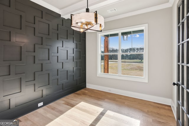 unfurnished dining area featuring crown molding, light hardwood / wood-style floors, and a chandelier