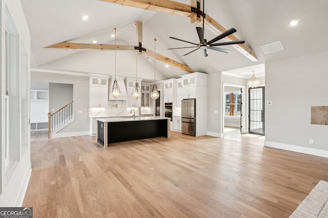 kitchen with stainless steel refrigerator, white cabinetry, an island with sink, hanging light fixtures, and light hardwood / wood-style flooring