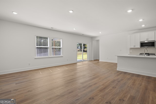 unfurnished living room with sink and light hardwood / wood-style flooring