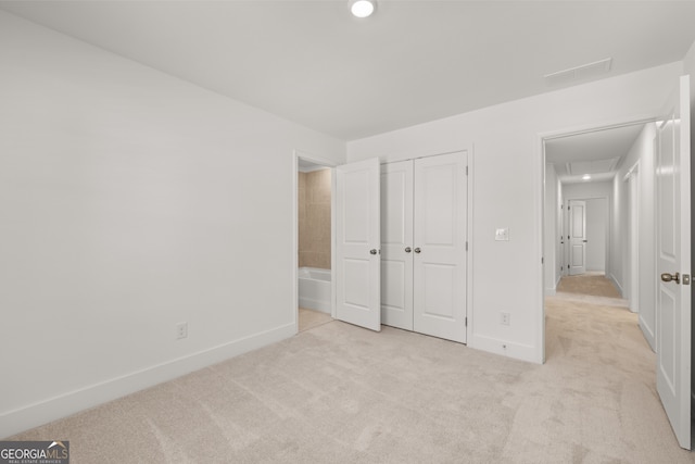 unfurnished bedroom with a closet and light colored carpet