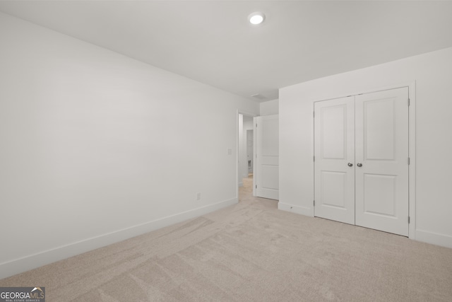 unfurnished bedroom featuring light carpet and a closet