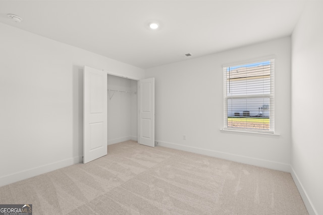 unfurnished bedroom with light colored carpet and a closet