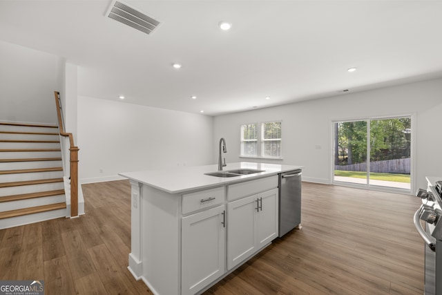 kitchen with sink, a kitchen island with sink, white cabinetry, stainless steel appliances, and light wood-type flooring