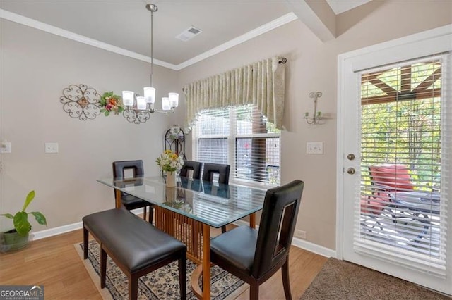 dining area featuring a notable chandelier, hardwood / wood-style flooring, ornamental molding, and a wealth of natural light