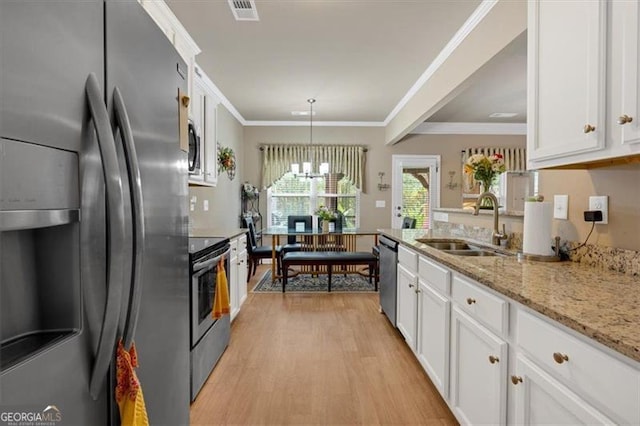 kitchen with white cabinets, light wood-type flooring, stainless steel appliances, and pendant lighting