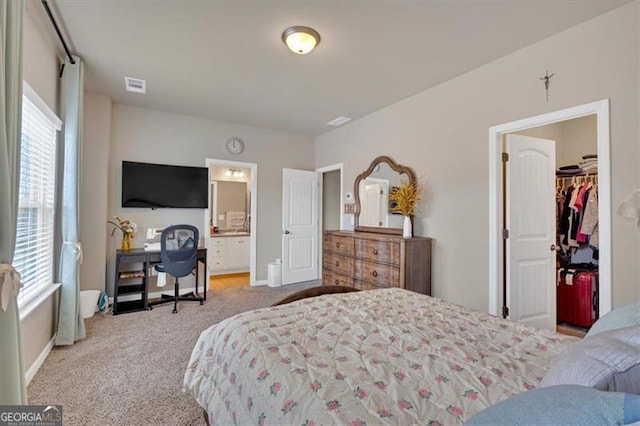 bedroom with light colored carpet, a closet, connected bathroom, and a spacious closet