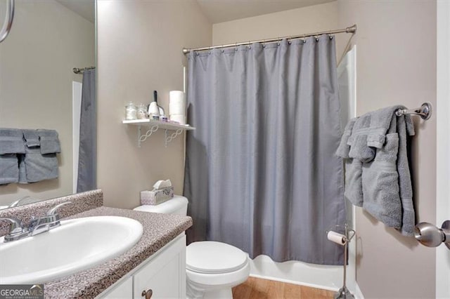 full bathroom featuring hardwood / wood-style floors, shower / tub combo with curtain, vanity, and toilet