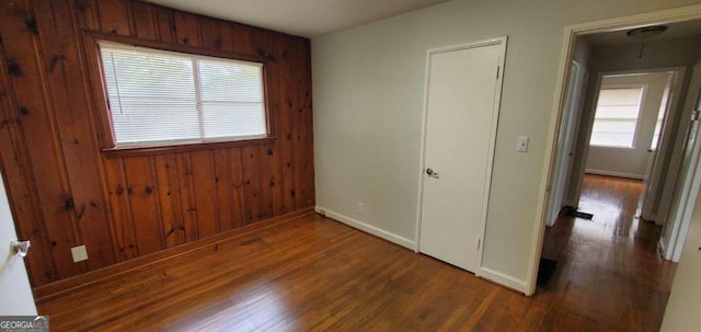 unfurnished bedroom featuring wood walls and dark hardwood / wood-style flooring