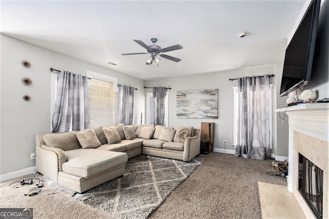 living room featuring ceiling fan, a premium fireplace, and carpet flooring